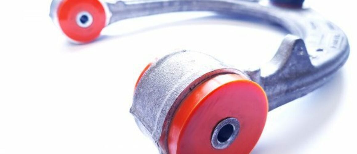 A close-up image of a silver and red car suspension arm and bushing isolated on a white background.