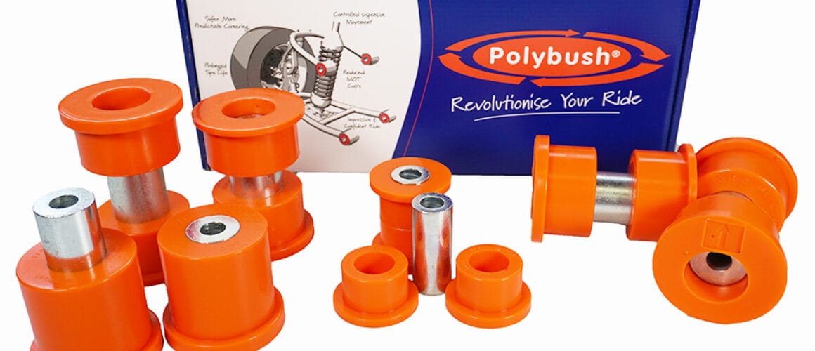 A collection of orange polyurethane suspension bushings and metal sleeves displayed in front of their packaging box labelled "polybush.