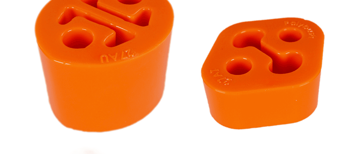 Two orange polyurethane exhaust hangers on a white background, labelled "fix exhaust rattles." The hangers feature a three-hole design and embossed text.