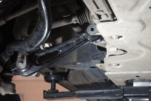 Close-up view of a car's undercarriage showing the suspension system, including shock absorbers and metal frame components.