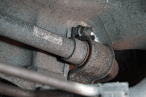 Close-up of a rusty metal pipe fitting with bolts and labels, showing signs of wear and corroding in an industrial setting.