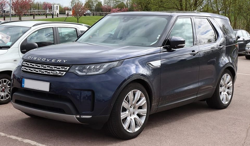 A blue Land Rover Discovery parked in a car park, featuring a modern design with sleek body lines and alloy wheels.