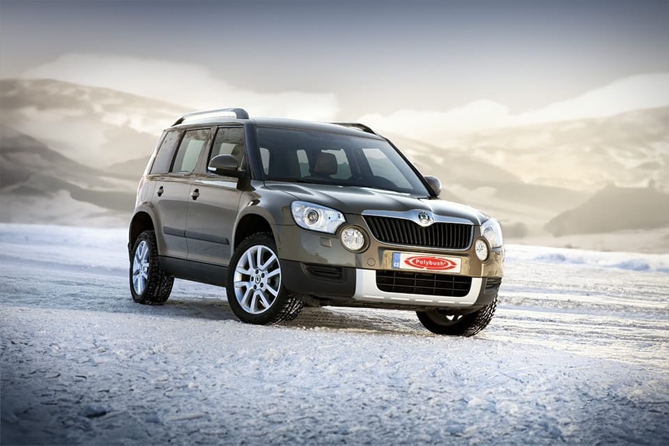 A silver 4x4 parked on a snowy landscape with misty mountains in the background during early morning light.