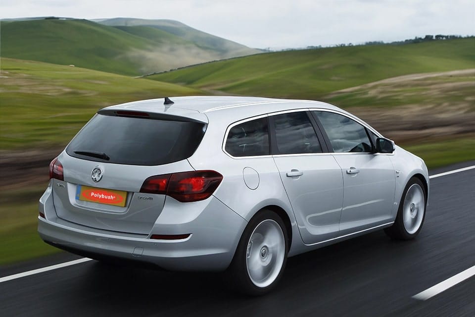 A white Volkswagen Golf TDI hatchback car driving smoothly on a motorway surrounded by lush green hills under a cloudy sky.