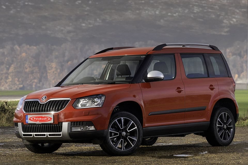 A red škoda yeti parked outside with a misty mountain backdrop, highlighting its robust body, large grille, and alloy wheels.