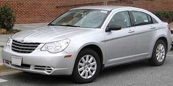 Silver saloon car parked on a street, featuring a curved front grill and five-spoke wheels.