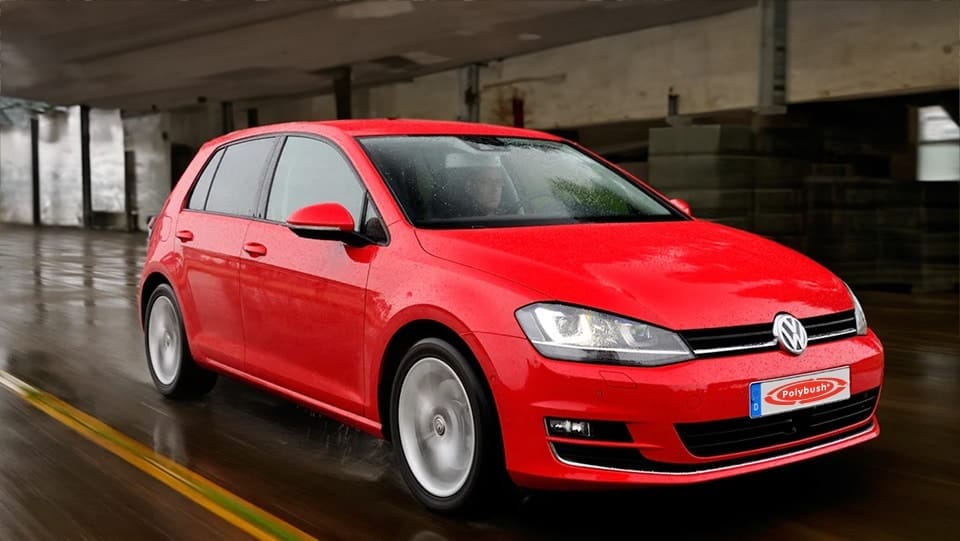 A red Volkswagen Golf parked in a dimly lit underground car park, with shiny wet floor reflecting the car's lights.