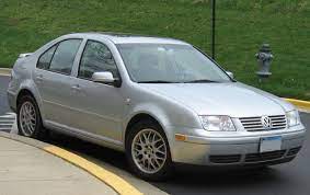 A silver Volkswagen saloon parked beside a kerb on a road, with green grass and a fire hydrant visible in the background.