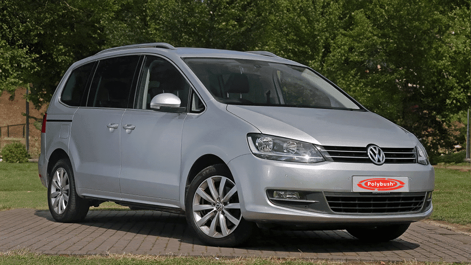 Silver Volkswagen people carrier parked on a paved area with a grassy background and trees, featuring a polybush logo on the front number plate.