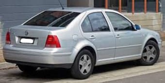 A silver saloon car parked on a road, viewed from a slighted angled rear perspective, featuring visible logos and clean lines.