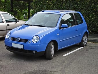 A bright blue Volkswagen hatchback car parked in a car park, featuring clean lines and compact design.